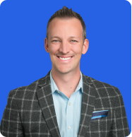 Headshot of a smiling man wearing a plaid blazer and light blue shirt, against a blue background.