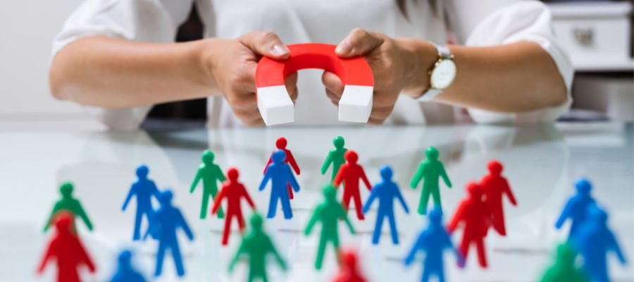 a person holding a magnet in front of a group of toy people, symbolizing lead generation