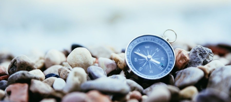 there is a compass on a pile of rocks near the ocean symbolizing navigating the complicated sea of lead management